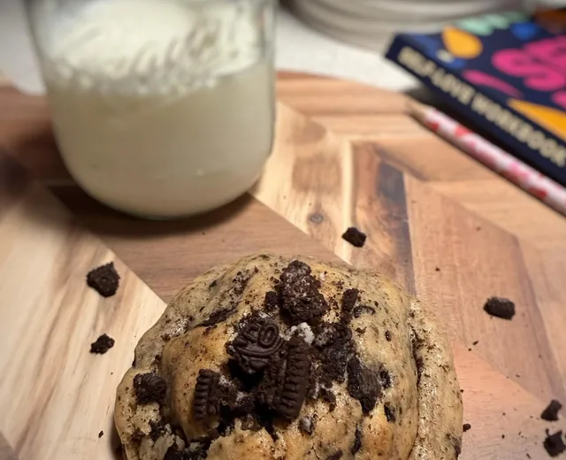 Cookies and cream cookie topped with chocolate cookie pieces beside a jar of milk